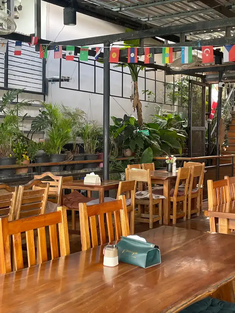 The inner room with wooden tables, potted plants and flags from many countries