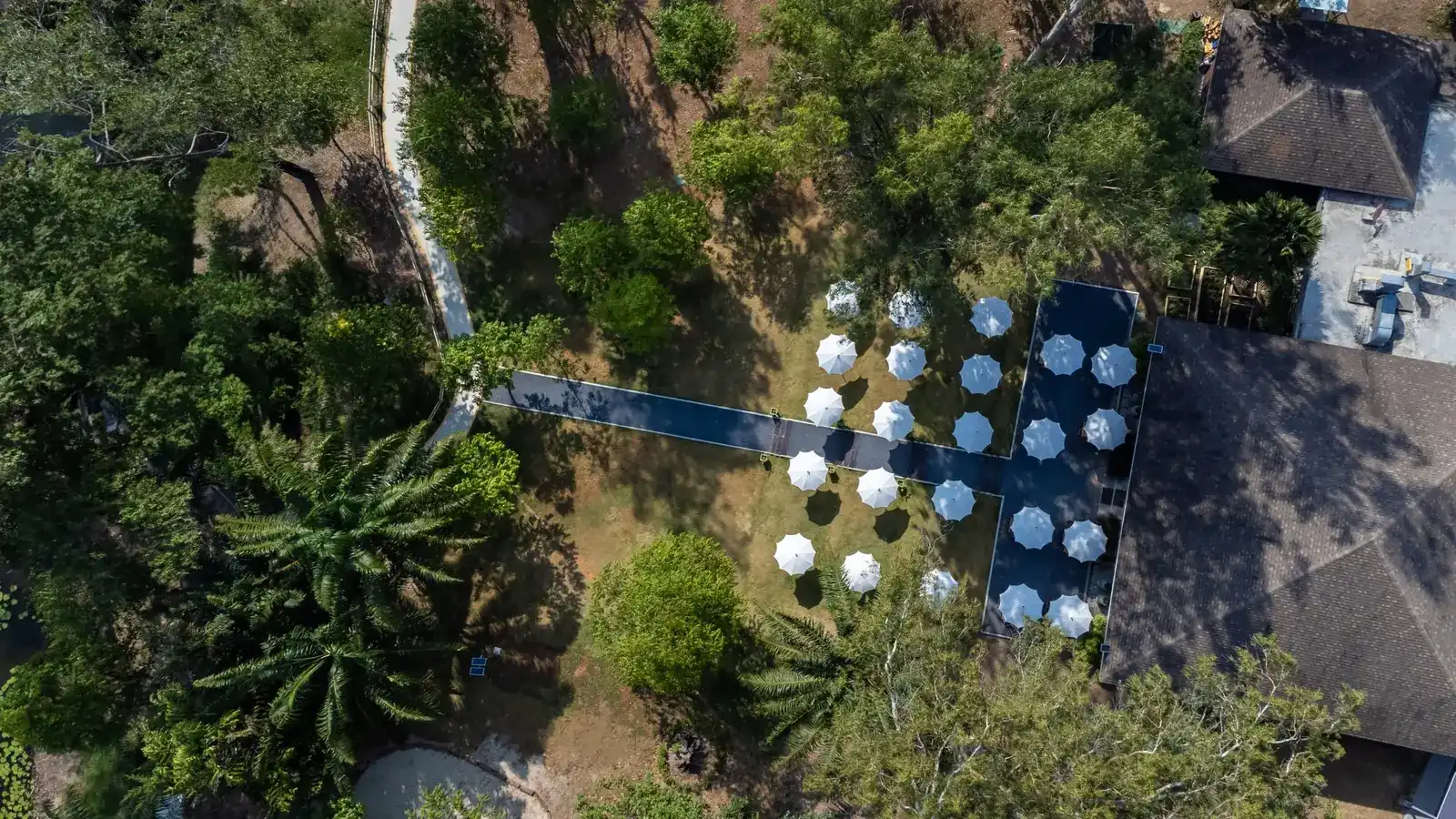 The park at Open Kitchen seen from above: white parasols on the lawn between the trees