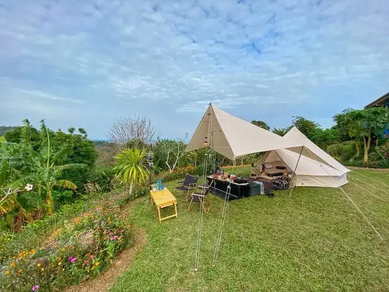 The camping lawn by day with a tent, chairs and a flower border