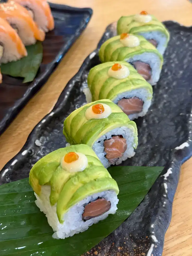 Avocado-wrapped rolls filled with salmon, topped with mayonnaise and fish roe