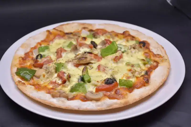 Thin-crust pizza with green peppers, olives, mushrooms and cheese