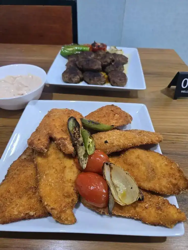 Golden breaded cutlets with grilled vegetables, grilled meat patties behind