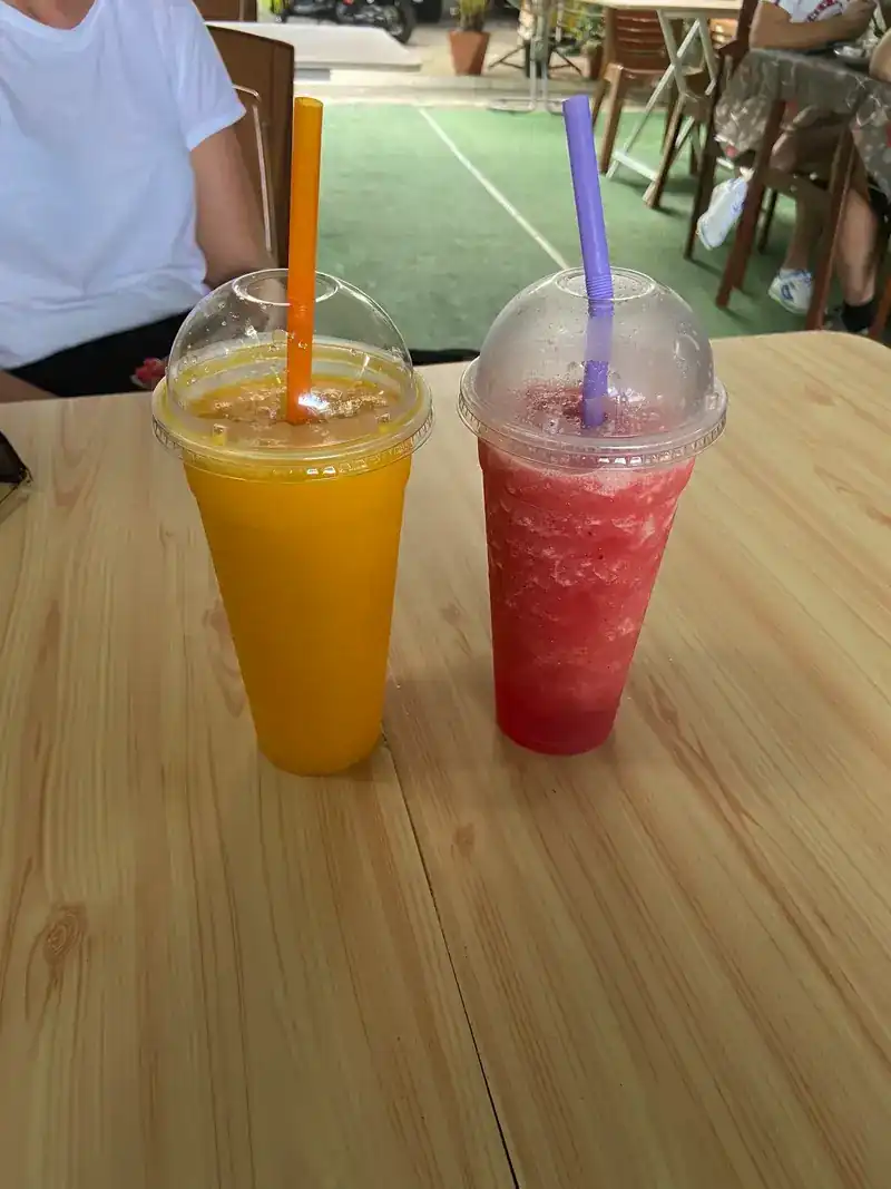 Two fruit shakes, one orange and one red, on a wooden table