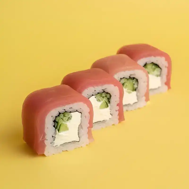 Tuna roll with cream cheese and cucumber on a yellow background