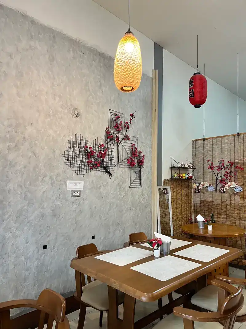 A corner of the dining room with a red lantern, bamboo blinds and wooden tables