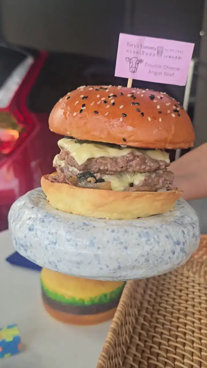 A double cheeseburger with its paper flag on a speckled stand