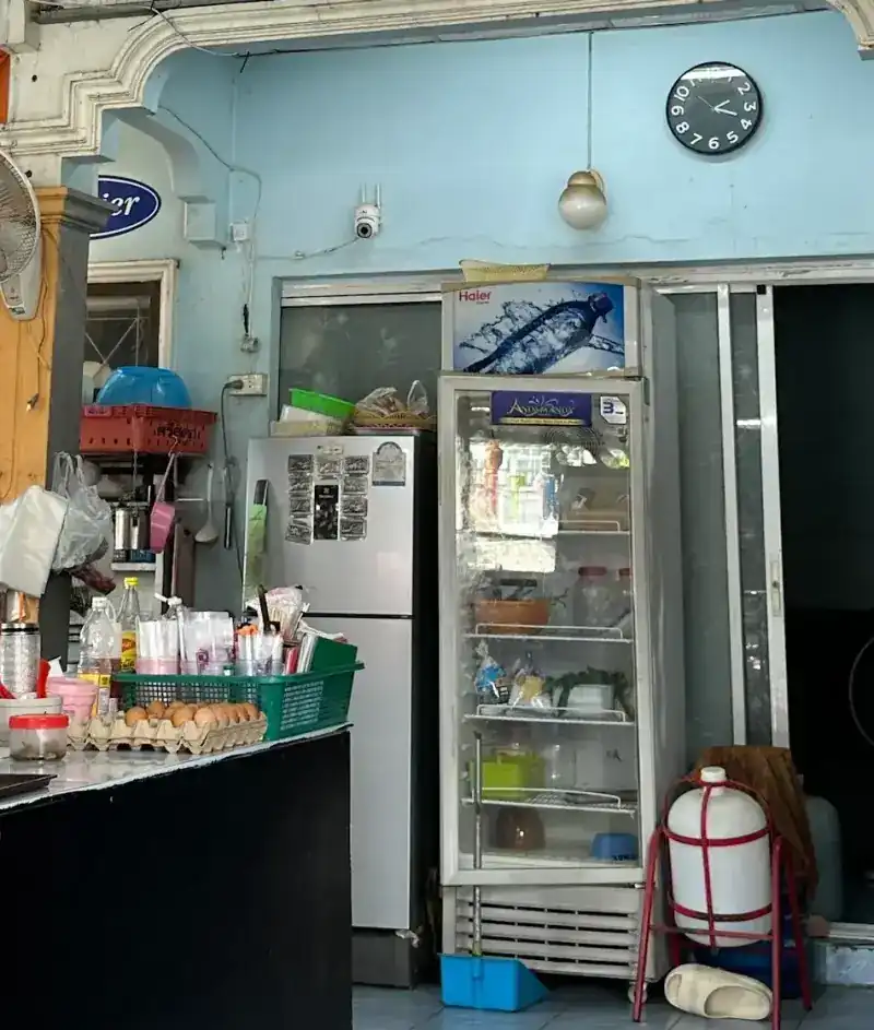 Inside the shop: the counter with eggs and sauces, a drinks fridge and a clock on the pale blue wall