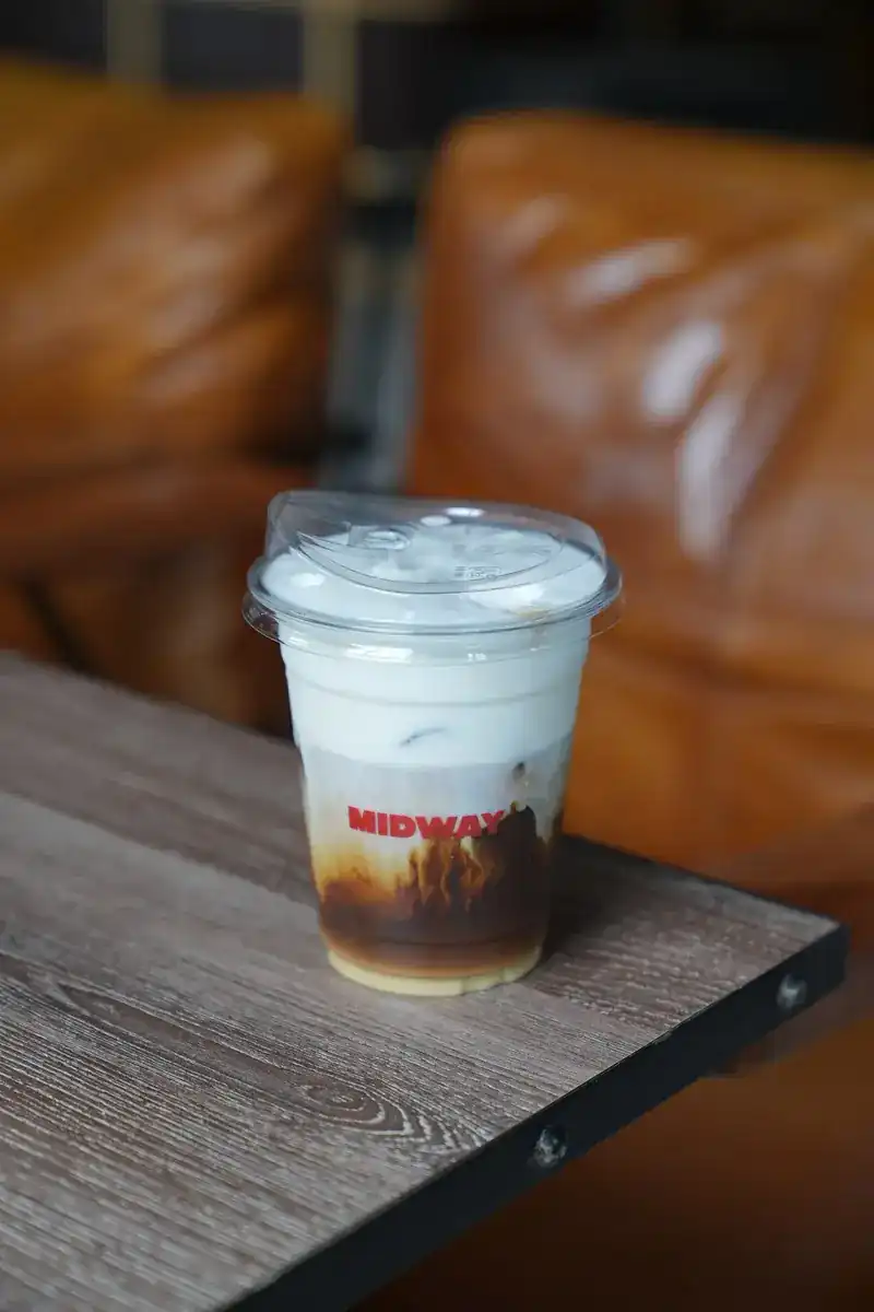 Iced coffee with milk foam in a Midway cup