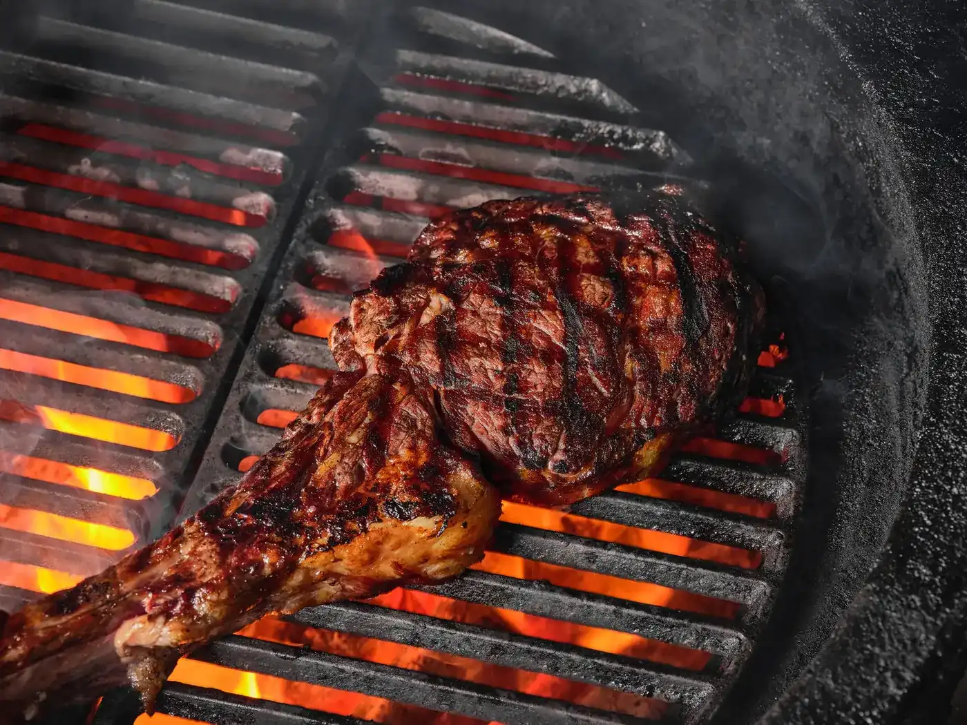 A tomahawk steak searing on the cast-iron grill over glowing coals