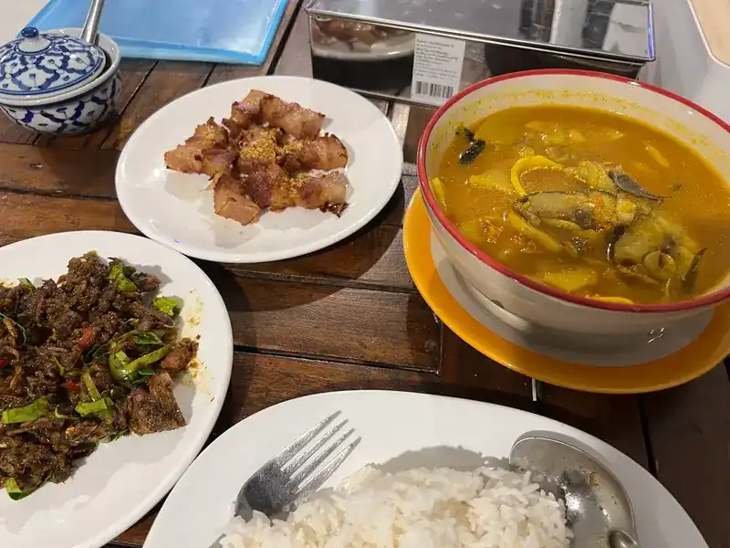 A table with a dry stir-fry, fried pork with garlic, a yellow curry and a plate of rice
