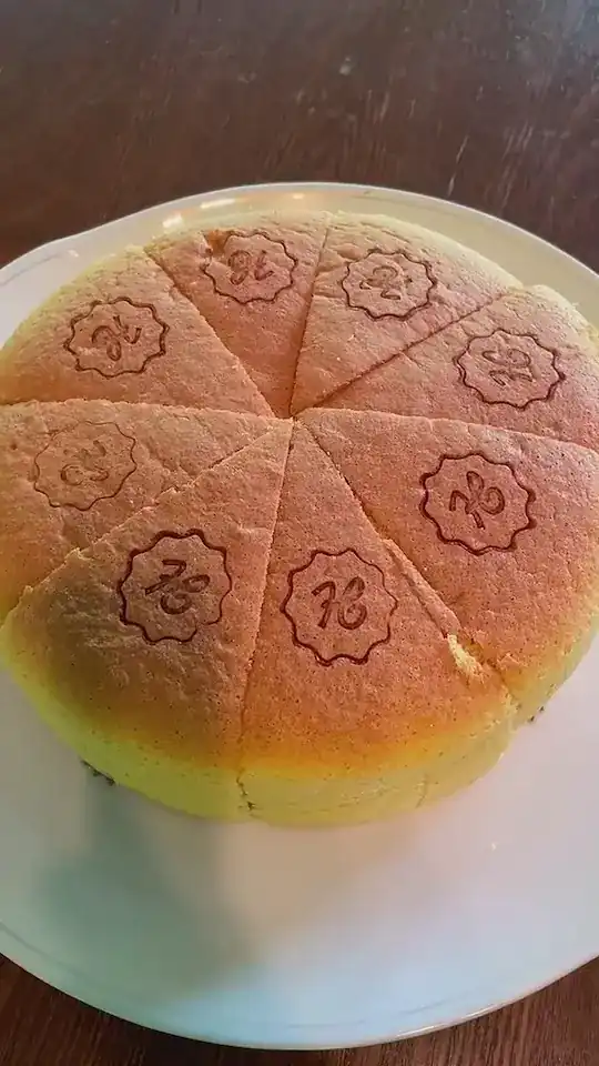 A round sponge cake cut into slices, each stamped with an H