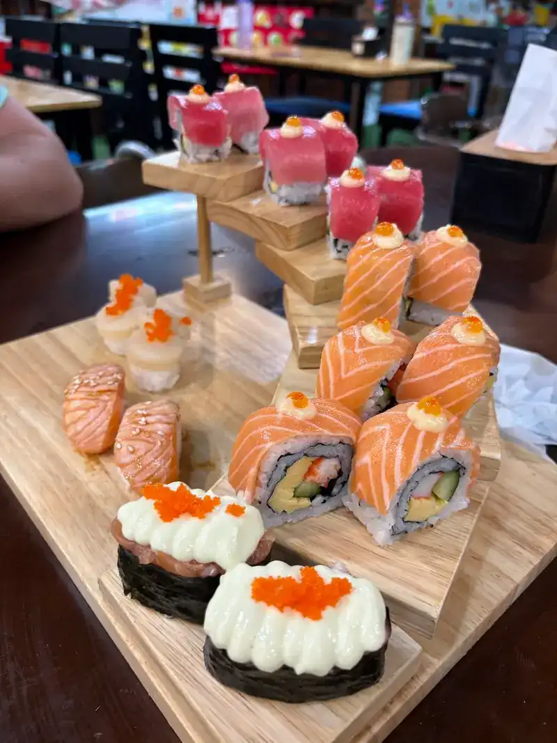 A wooden sushi tower: tuna on top, salmon rolls in the middle, gunkan with roe at the front