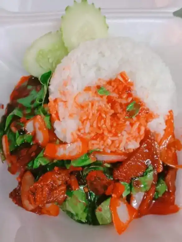 A stir-fry in red sauce over rice, packed in a takeaway box with cucumber