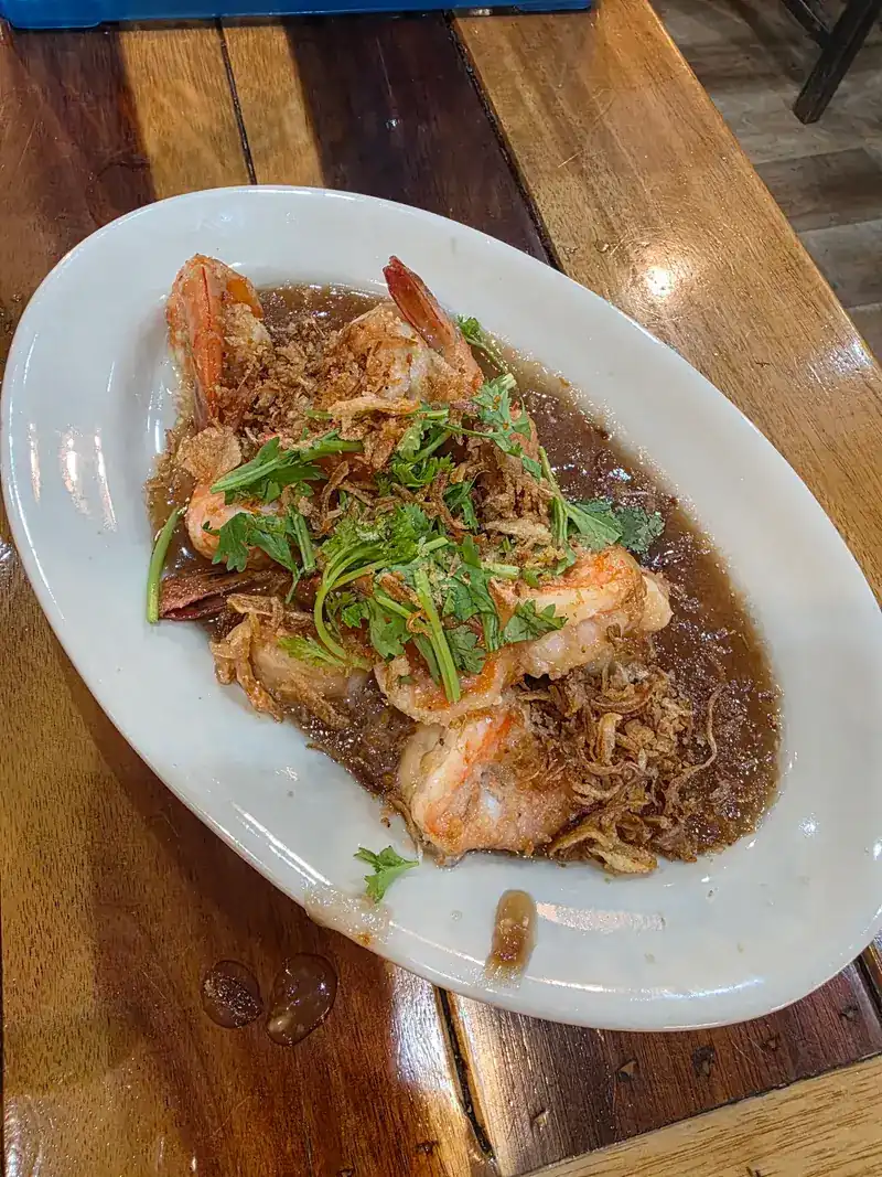 Prawns in a dark glossy sauce with fried shallots and coriander