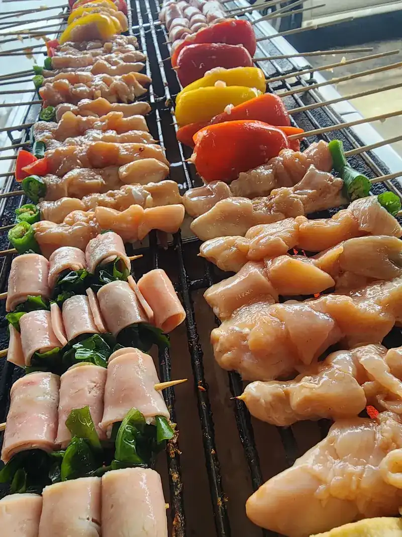 Chicken and sweet pepper skewers next to wrapped rolls