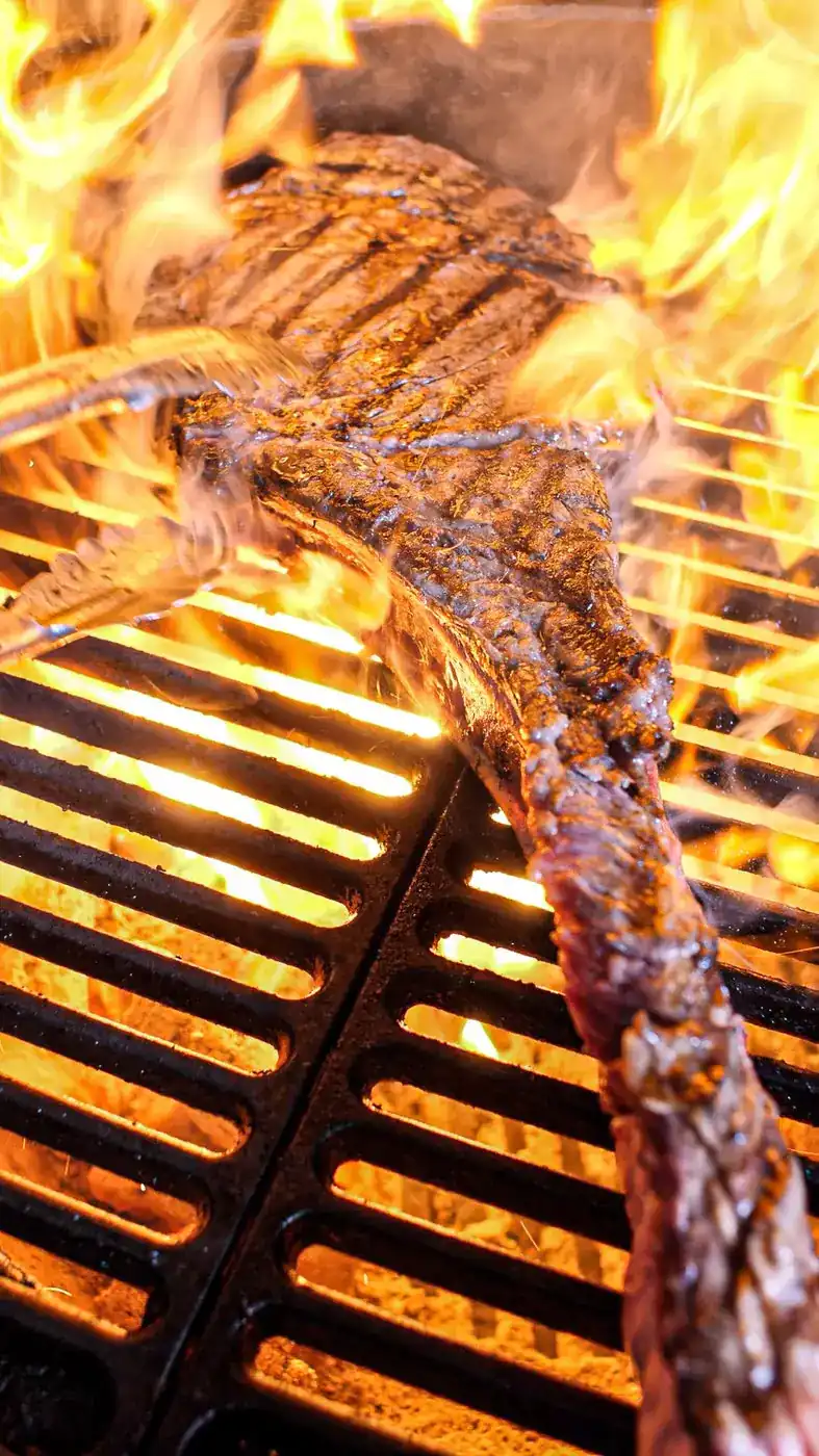 The steak on a cast-iron grate with flames rising around it