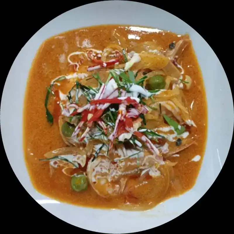 Prawn curry on a white plate with red chili and kaffir lime leaf