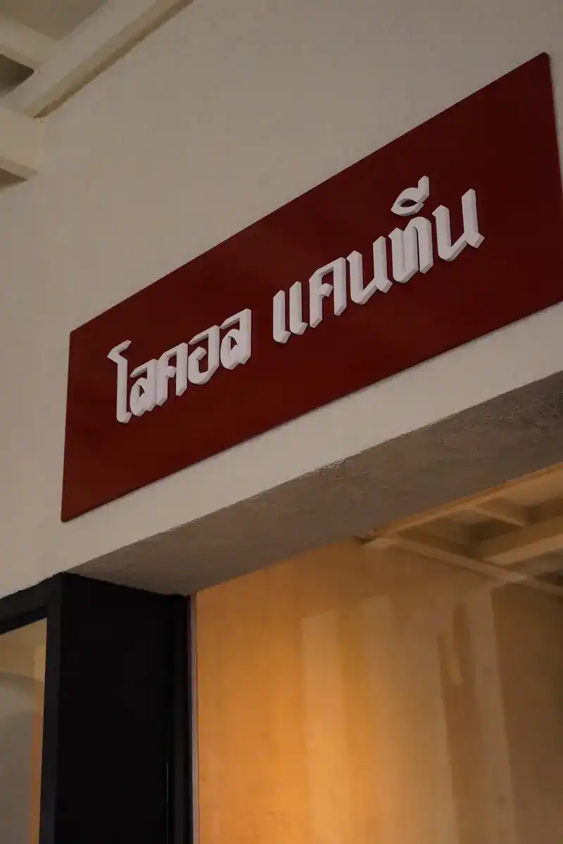 The dark red sign with white Thai lettering above the door