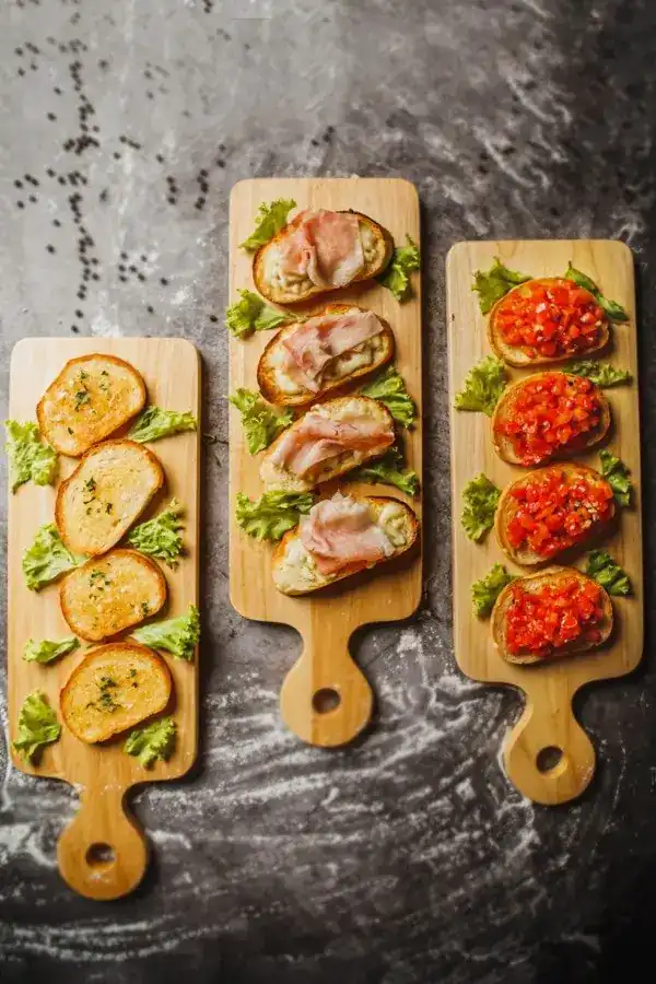 Three boards of bruschette: garlic, mozzarella and ham, fresh tomato