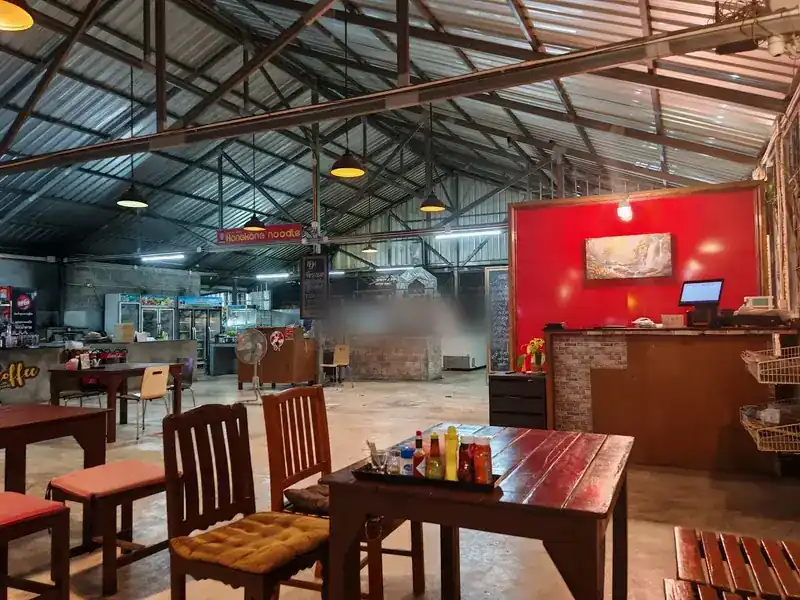 The open hall with wooden tables, the Hong Kong noodle sign and the grill at the back