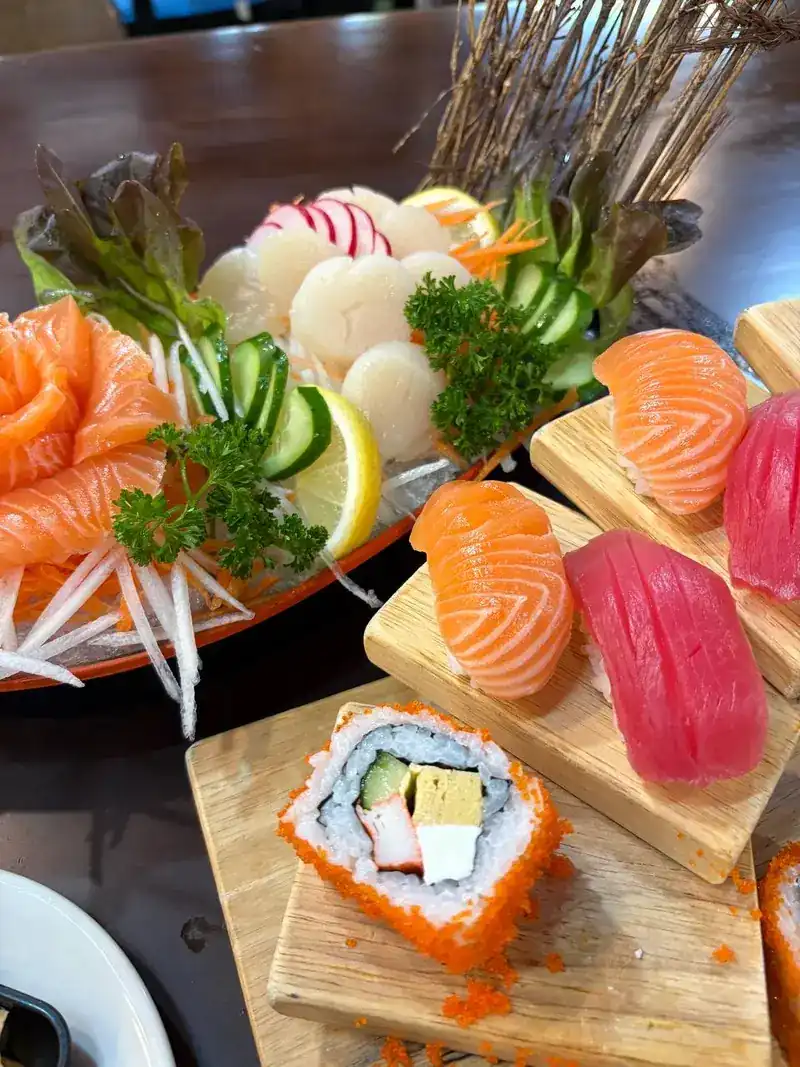A salmon sashimi plate beside salmon and tuna nigiri and a roll, each on its own wooden block