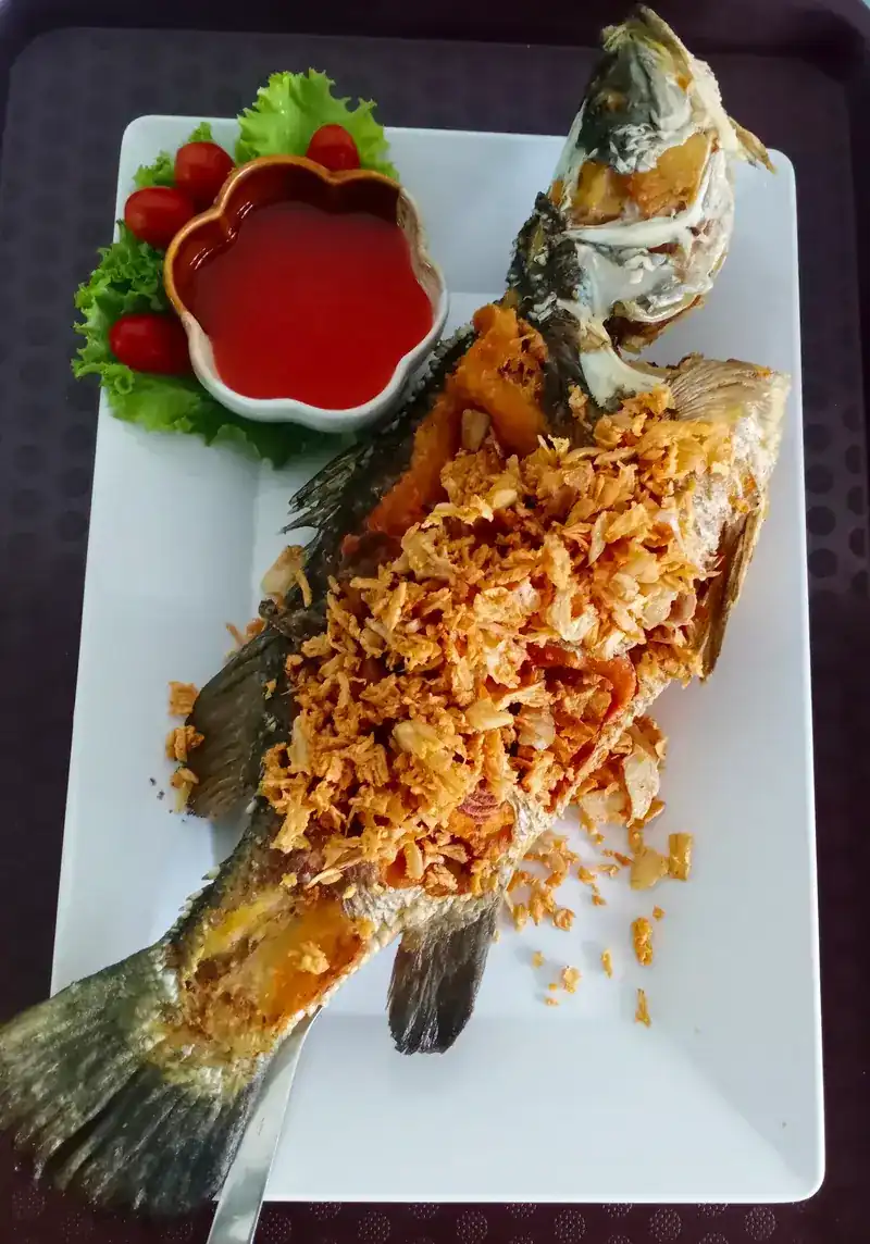 A whole fried fish under a crisp-fried topping, with chilli sauce on the side